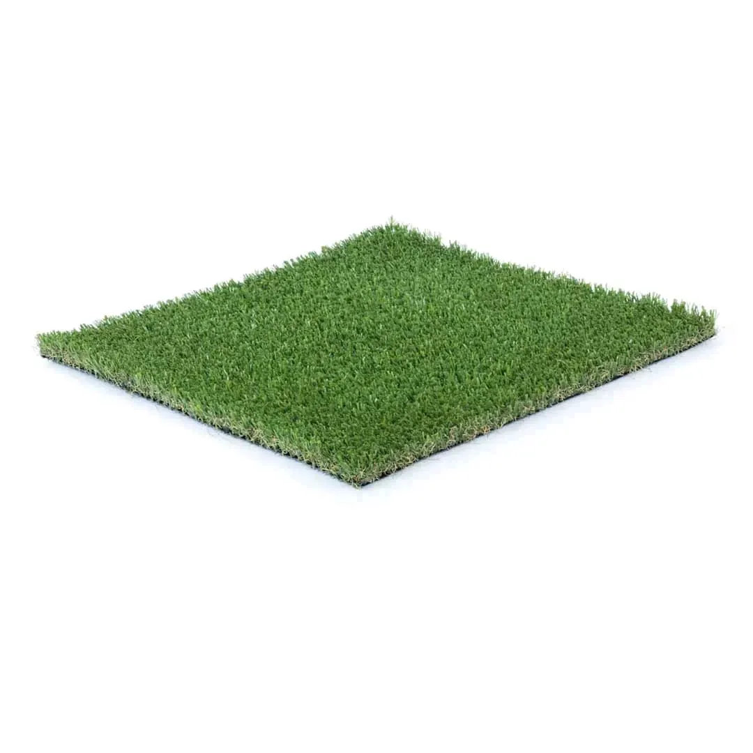 A square sample of green artificial turf seen at an angle, dense blades in two shades of green with the pale thatch showing along the cut edges