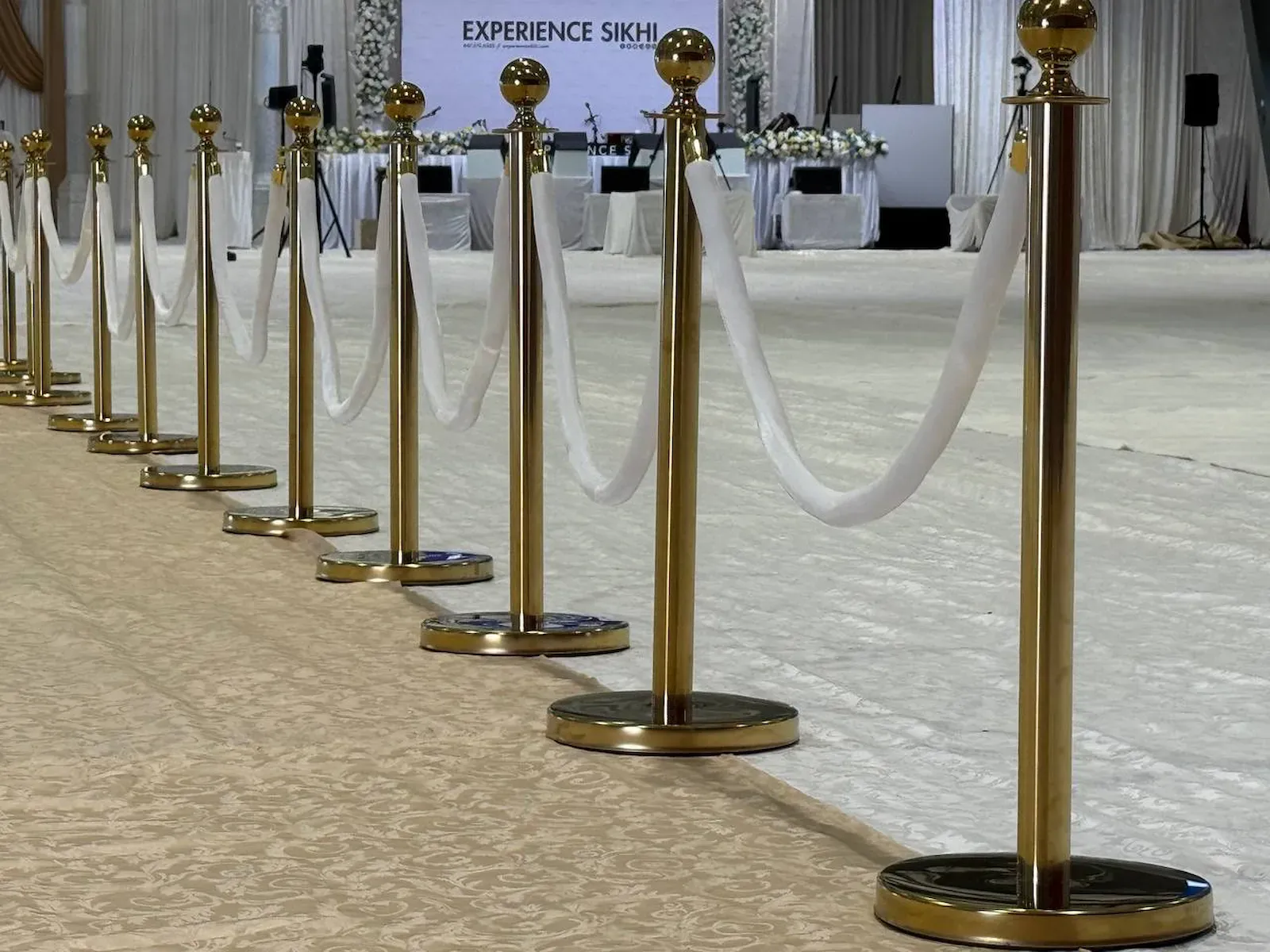 White ropes swagged between gold posts down the edge of a patterned banquet carpet